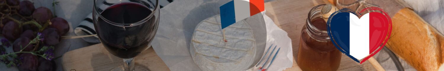 Weine aus Frankreich: Französische Weinflaschen und Gläser auf einem Tisch mit Käse, Baguette und Trauben, im warmen Licht.